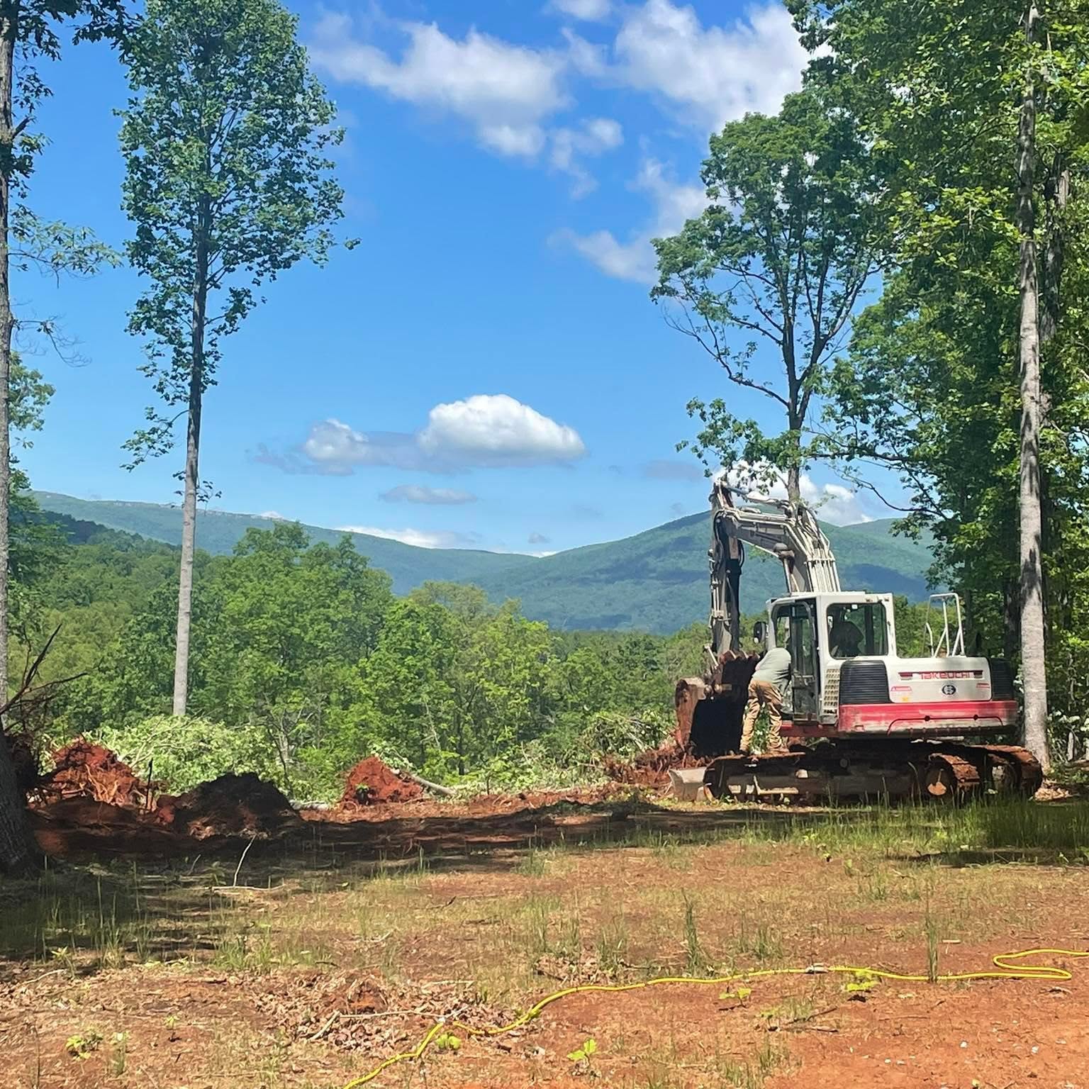 Excavator clearing land with Blue Ridge mountain view